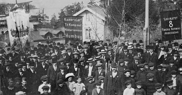 1. mai på Slemmestad i Røyken, 1909. Fanen til venstre tilhører Slemmestad Arbeiderforening. Paroler: Kamerater! Til Kamp mot Militarismens Humbug; Lovfæstet 8 timers normal arbeidsdag.